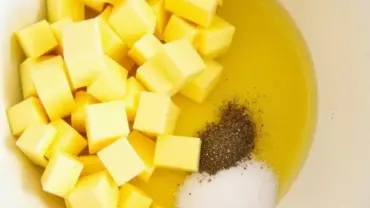 Yellow squash, olive oil, salt, and pepper in a bowl