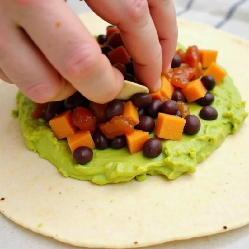 Assembling a vegan breakfast burrito with black bean and sweet potato filling