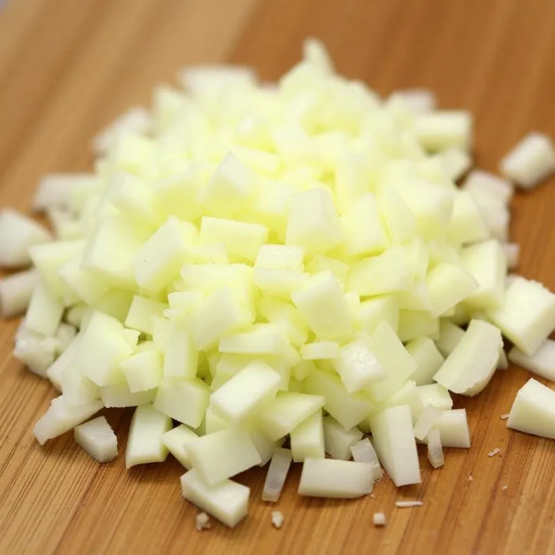 A yellow onion finely chopped on a cutting board