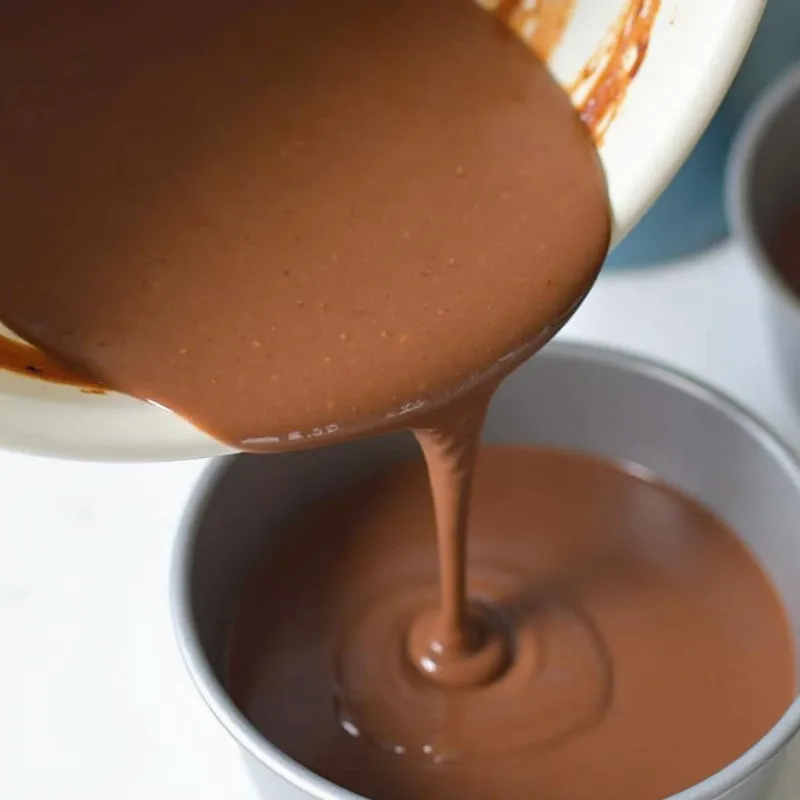 Pouring vegan cake batter into prepared cake pans