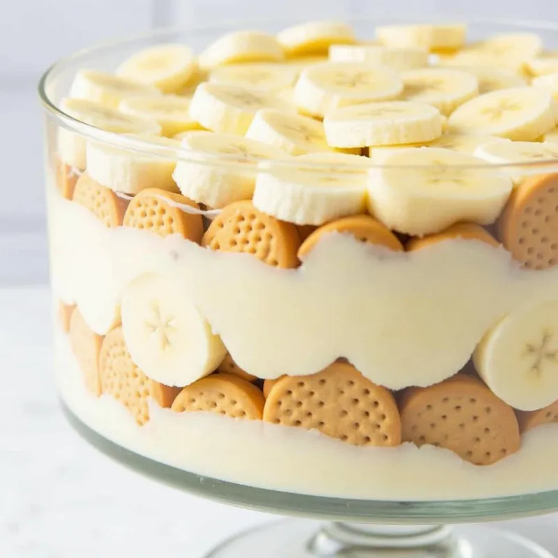 Layering vegan banana pudding in a trifle dish.