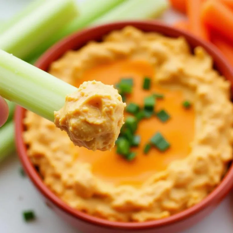 Vegan Buffalo Chicken Dip with celery sticks and carrots.