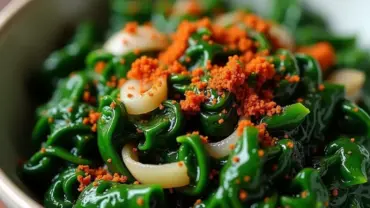 Steaming bowl of vegan collard greens with smoked paprika and onions.