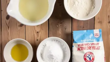 Vegan pizza dough ingredients laid out on a wooden table