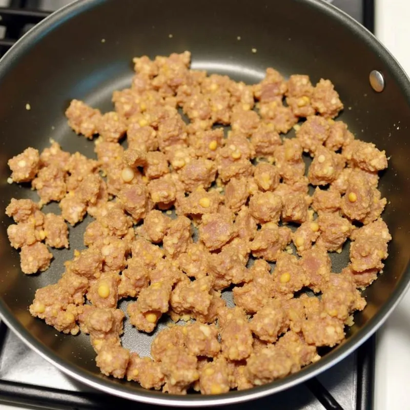 Vegan sausage being browned in a skillet for a flavorful base for the gravy.