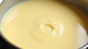 Vegan vanilla pudding cooking in a saucepan on the stovetop.